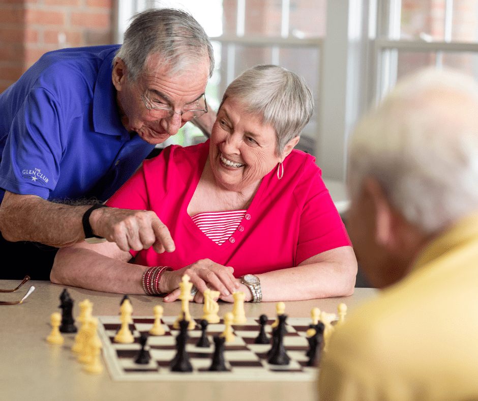 Seniors joyfully engaged in a chess game, sharing laughter and companionship in a bright, welcoming environment.