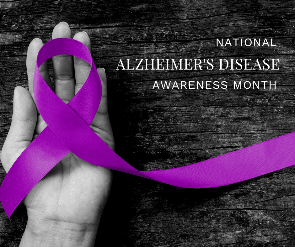 Purple ribbon in a hand, symbolizing Alzheimer's Disease Awareness Month with a wooden background.