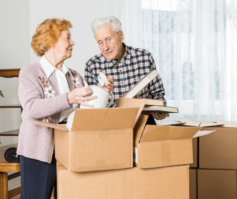 Couple joyfully unpacking moving boxes in a bright, airy living space, surrounded by personal items and a warm atmosphere.