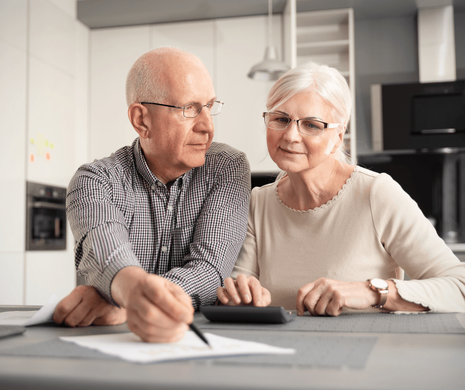 Senior couple engaging in thoughtful conversation at a modern kitchen table, surrounded by papers and a calculator.