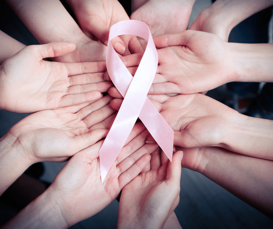 Hands of diverse individuals gather together, holding a pink ribbon symbolizing support for breast cancer awareness.