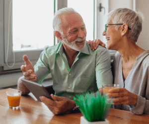 2-12-25 - Grace Management Senior man and woman sitting at table laughing holding a tablet