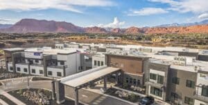 Modern senior living community surrounded by stunning red rock mountains and upscale amenities under a bright blue sky.