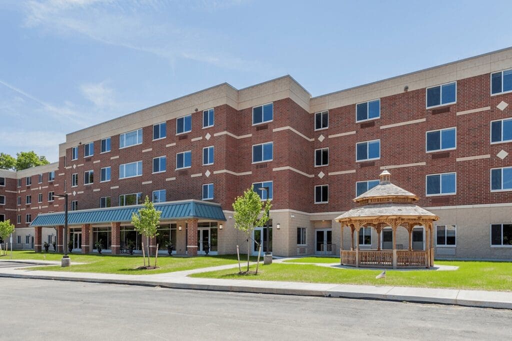 Elegant senior living facility with vibrant landscaping and a charming gazebo, designed for a compassionate lifestyle.