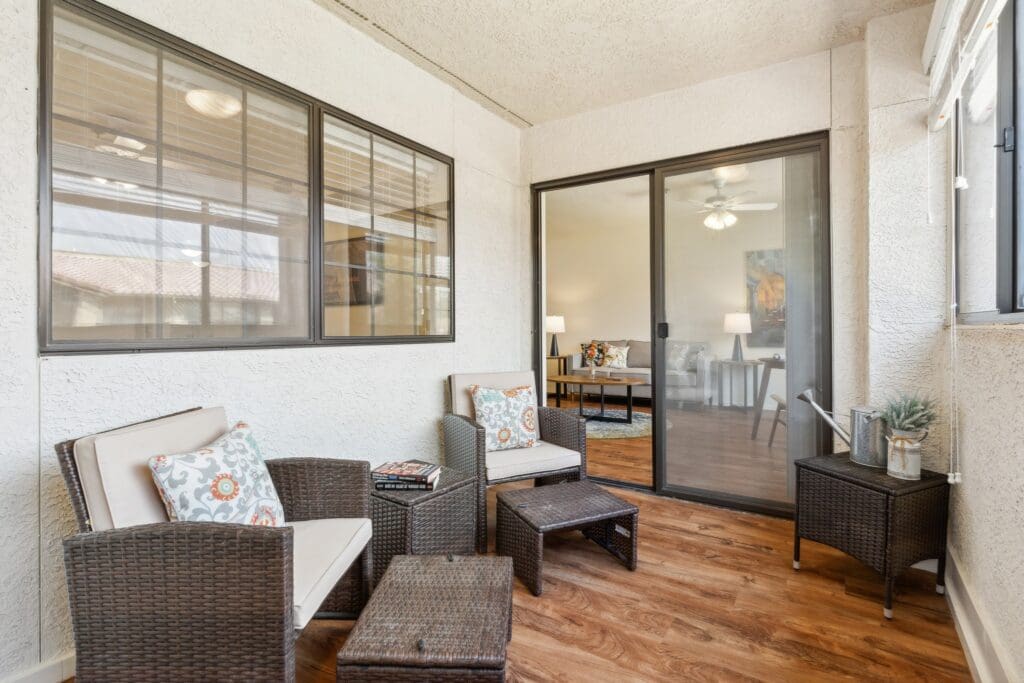 Bright sunroom featuring stylish wicker seating, elegant decor, and an inviting view of a comfortable living space beyond.