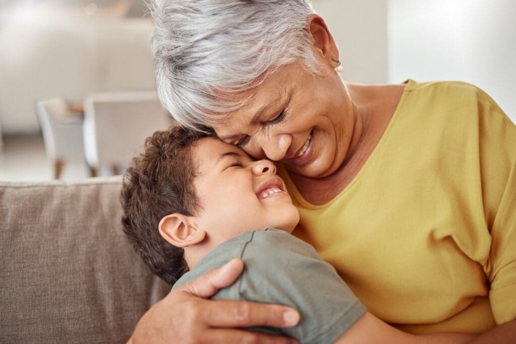 A joyful moment between a smiling grandmother and her grandson, sharing a warm embrace indoors.