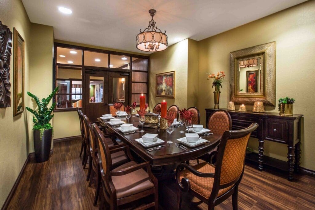Elegant dining room featuring a large, polished table set for a meal, surrounded by tasteful decor and warm lighting.