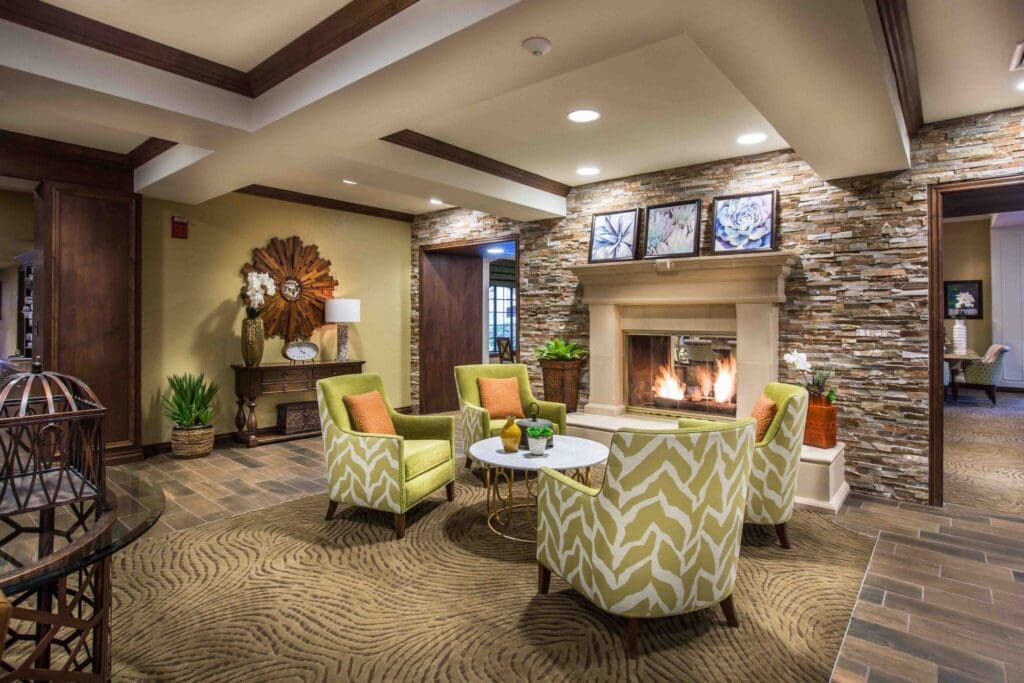 Cozy lounge with elegant green chairs, a fireplace, and decorative accents, creating a warm, inviting atmosphere.