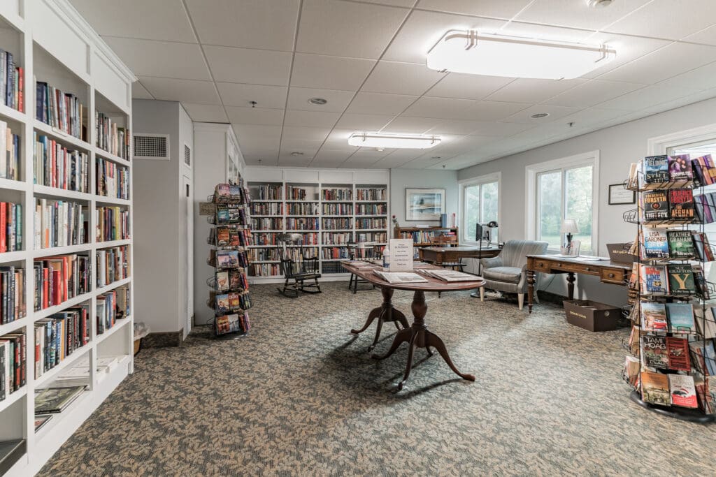Cozy library filled with books, reading chairs, and a table, offering a serene space for residents to relax and engage.