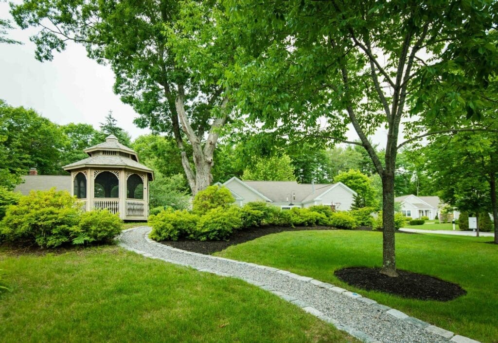 Lush green garden with a winding stone path leading to a charming gazebo, surrounded by vibrant landscaping and serene nature.