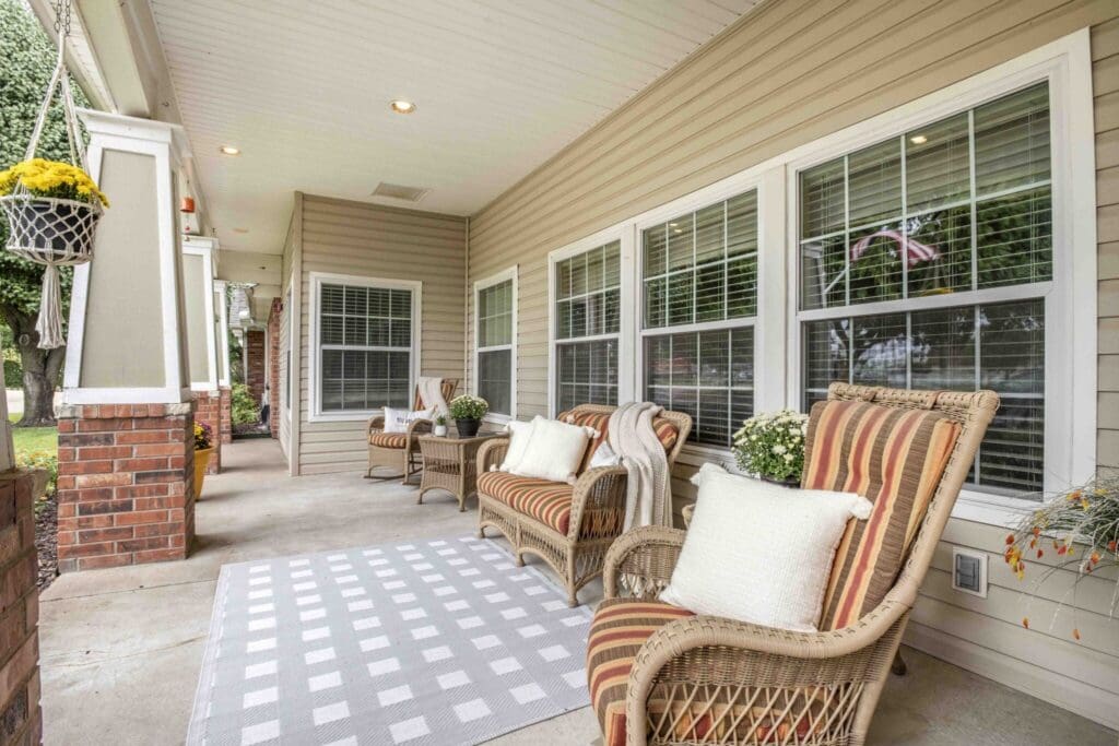 Charming porch with inviting wicker chairs, cozy cushions, and potted flowers, creating a warm, welcoming atmosphere.