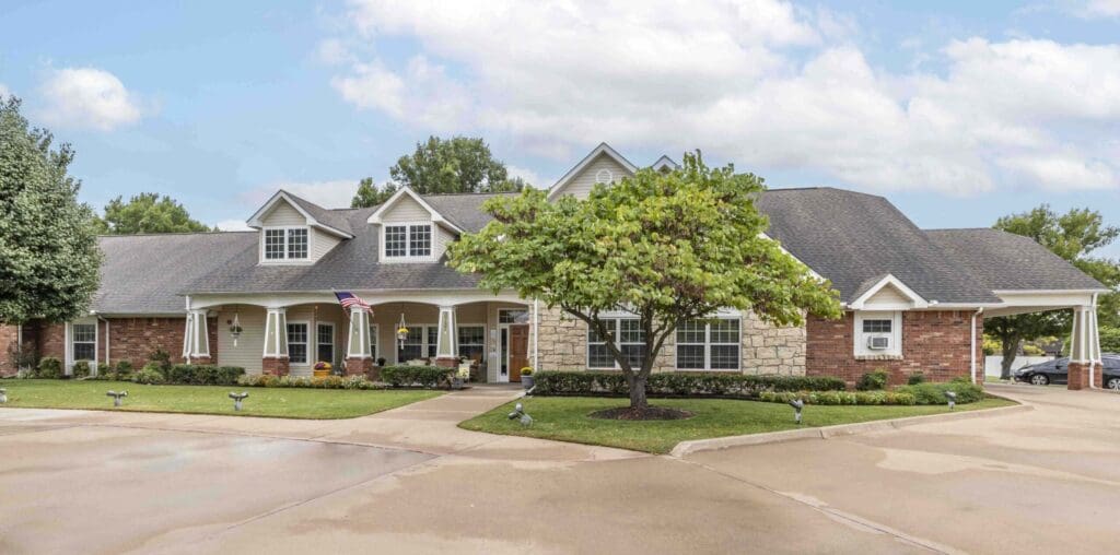 Charming senior living community with lush landscaping, welcoming entrance, and a blend of brick and stone architecture.