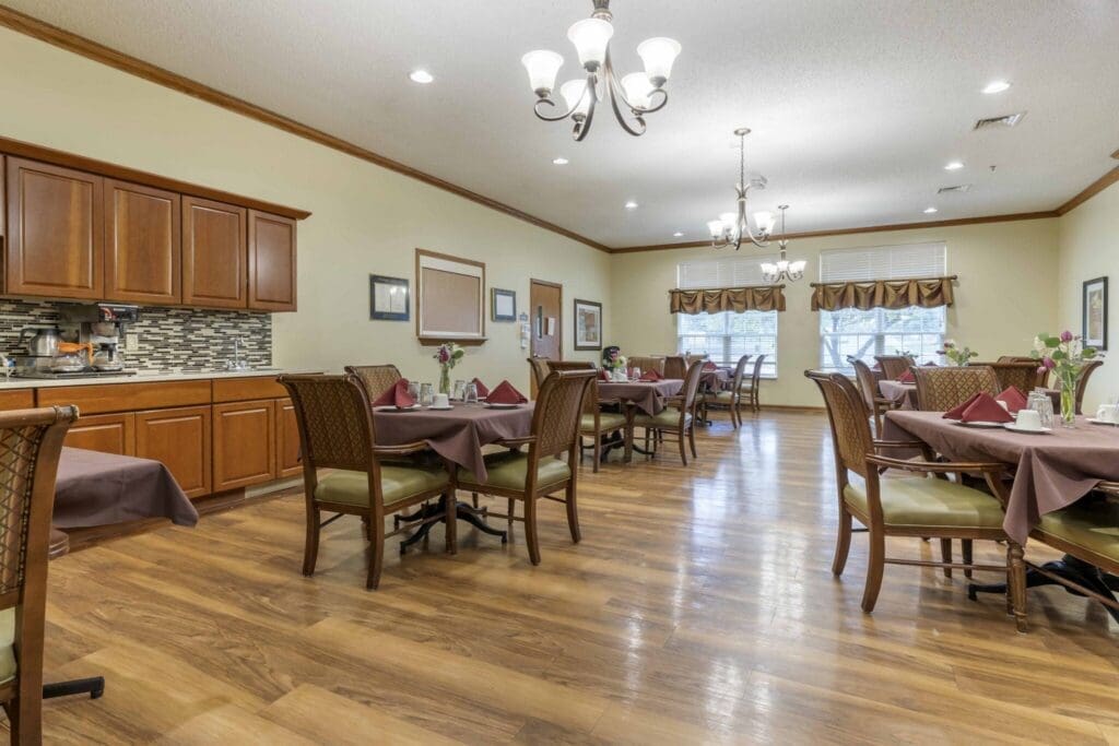 Elegant dining area with wooden tables, green chairs, and tasteful floral accents, promoting a vibrant community atmosphere.