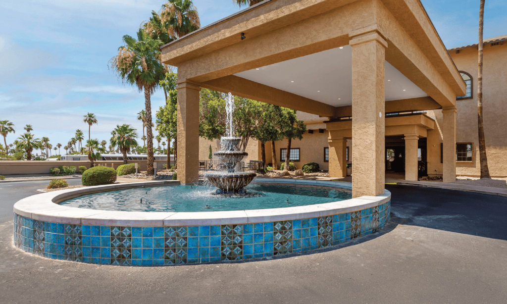 Elegant entrance featuring a tiered fountain surrounded by lush palm trees, exuding a welcoming and vibrant atmosphere.