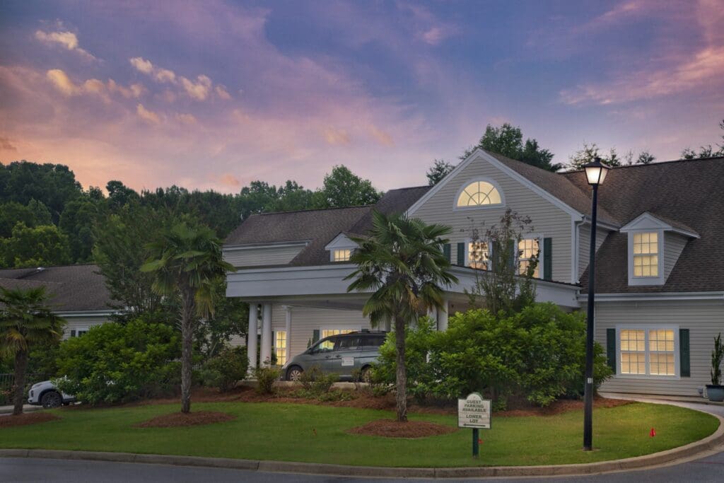 Charming senior living community at sunset, featuring lush landscaping, elegant architecture, and warm, welcoming ambiance.