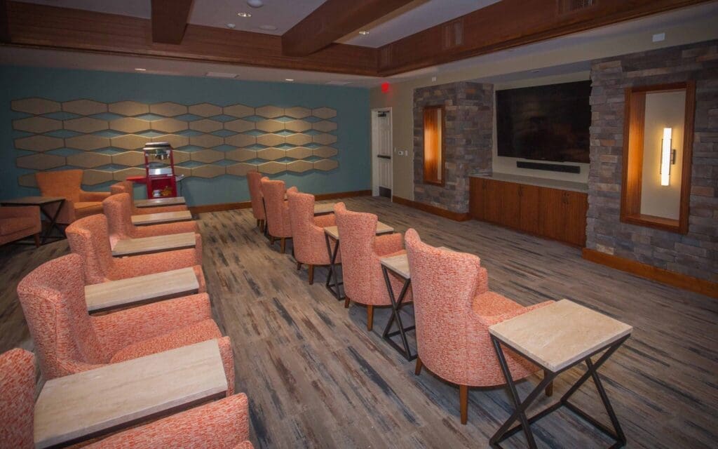 Sage-Desert-Tucson-AZ-2018-June-0222-2048x1280 - Grace Management Inviting lounge featuring modern decor, cozy orange chairs, and a large TV, perfect for socializing and relaxation.