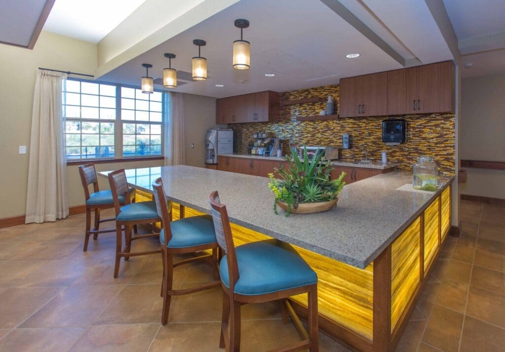 Sage-Desert-Tucson-AZ-2018-June-0331-2048x1428 - Grace Management Bright, inviting kitchen with a granite countertop, stylish seating, and vibrant decor, fostering a warm community atmosphere.
