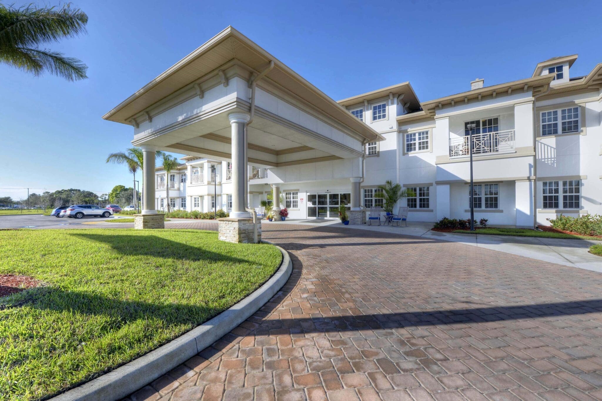 A sitting are with beige, blue, and green sofa chairs, fireplace, and white bookshelves that are built into the wall at Beach House, a senior living community.