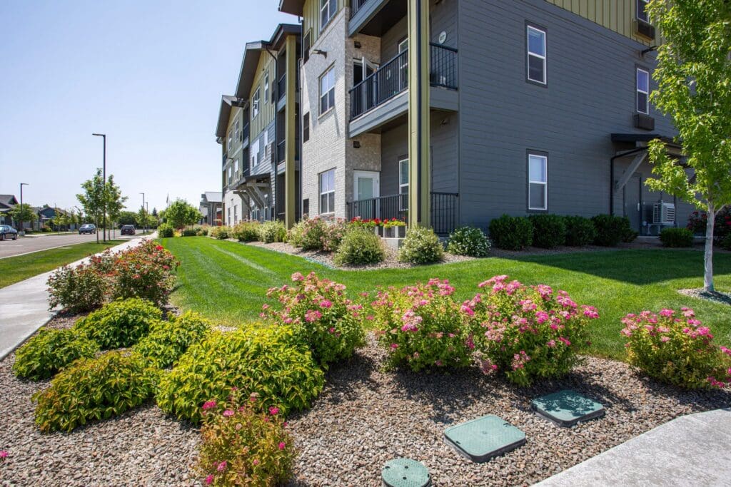Lush landscaping with vibrant flower beds alongside a modern senior living community, showcasing a welcoming atmosphere.