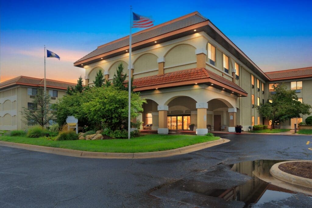 Upscale senior living community entrance with welcoming ambiance, lush landscaping, and vibrant twilight sky.