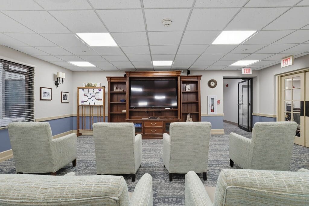Elegant common area featuring inviting chairs, a large TV, and warm lighting, fostering a vibrant community atmosphere.