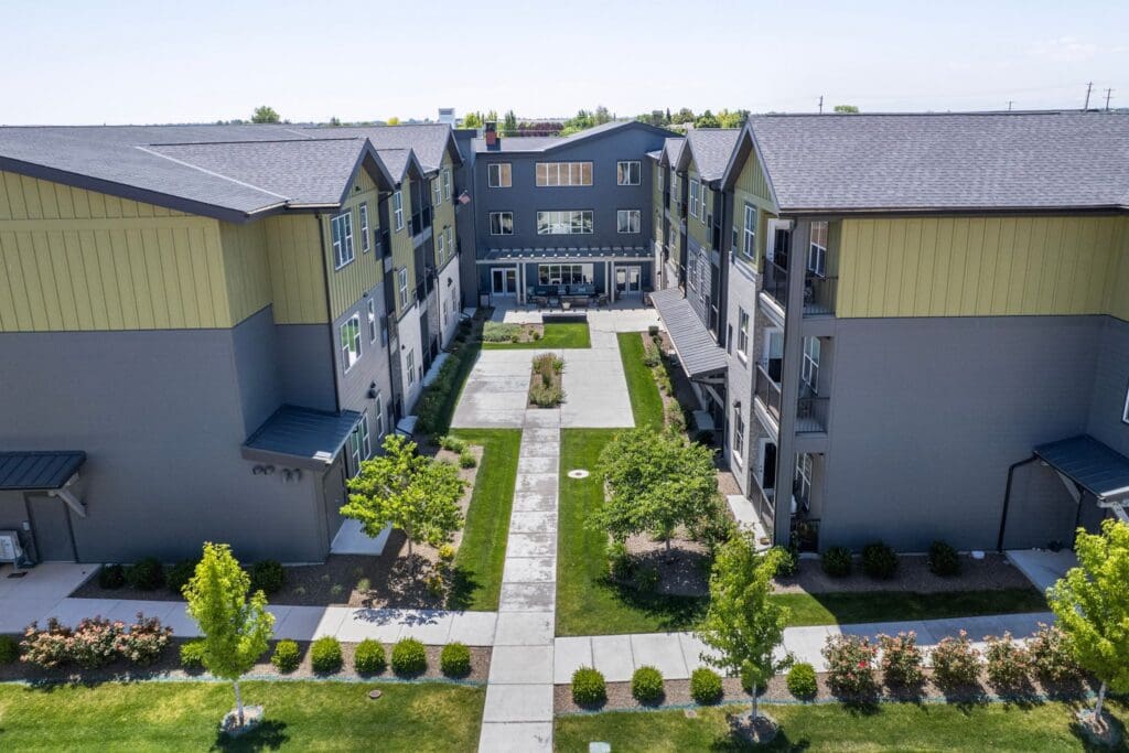 Lush green pathways weave between modern residential buildings, showcasing serene outdoor spaces and vibrant landscaping.
