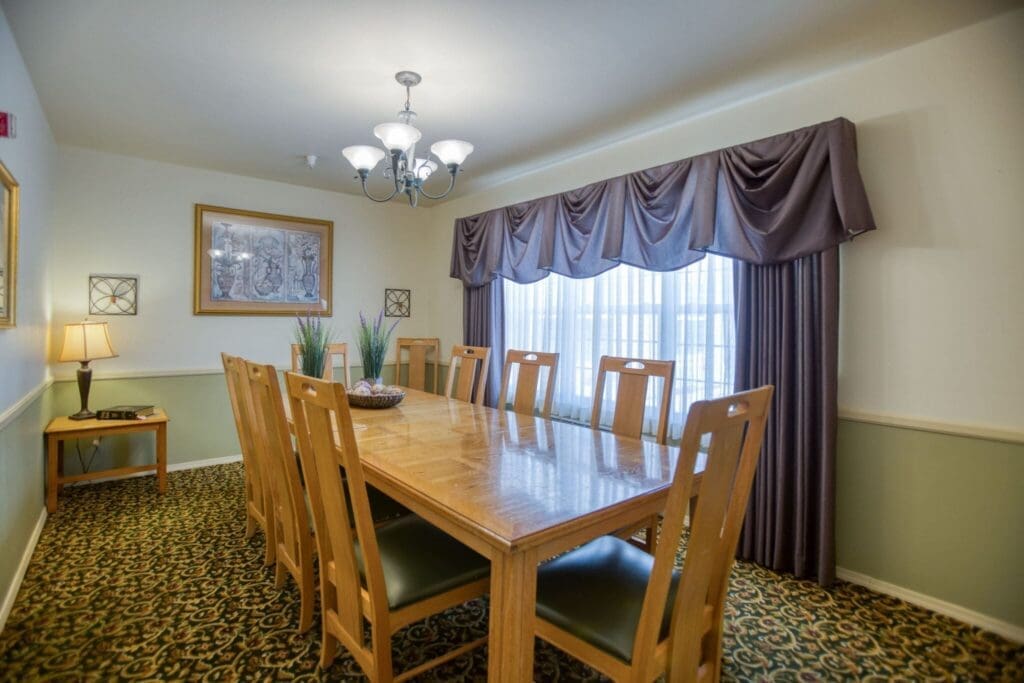 Elegant dining room featuring a long wooden table, plush seating, and warm lighting, perfect for vibrant gatherings.