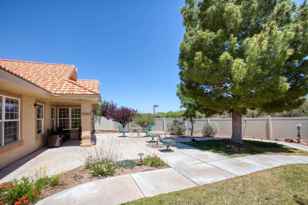 Beautifully landscaped outdoor patio featuring seating, vibrant greenery, and a clear blue sky, ideal for relaxation and community.