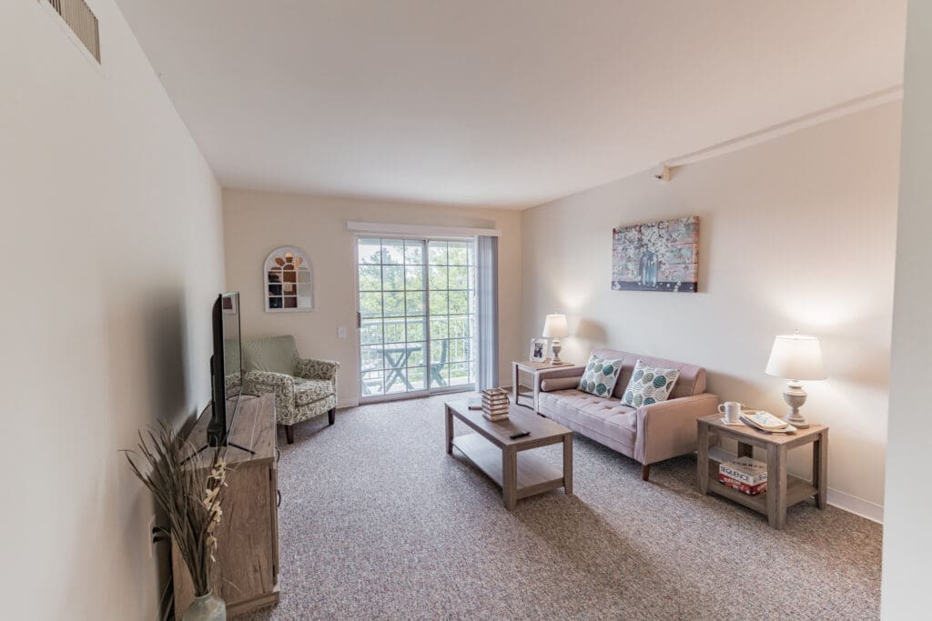 Bright and inviting living space featuring a cozy sofa, elegant decor, and large windows with nature views.