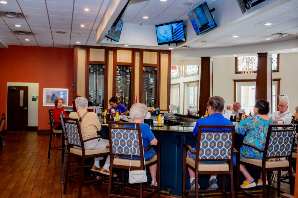 Seniors enjoy lively conversation at a stylish bar, highlighting community connection in an upscale senior living environment.