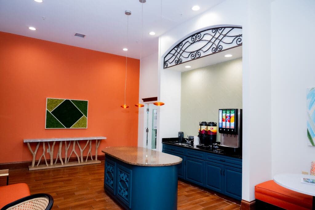 Vibrant community lounge featuring stylish decor, a welcoming service counter, and beverage station for residents to enjoy.