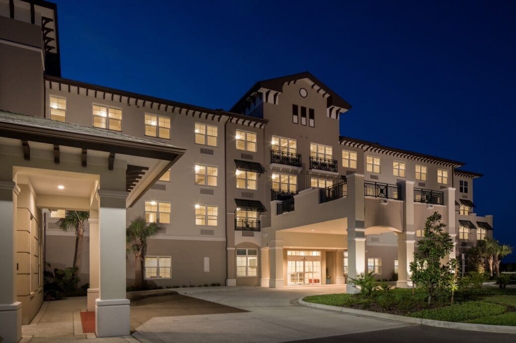 Elegant senior living community entrance, showcasing upscale architecture and inviting landscaping at twilight.
