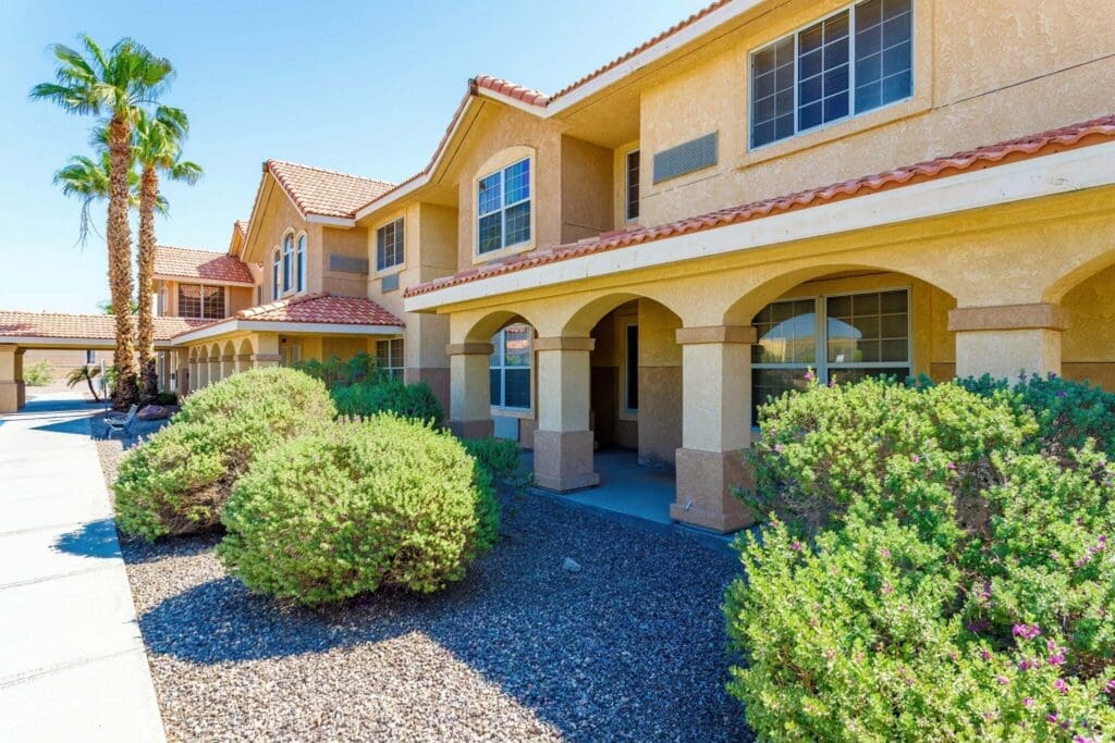 2022_LakeHavasu_EXT-Front_55-2048x1365 - Grace Management Elegant senior living community featuring arched entryways, vibrant landscaping, and a sunny, welcoming atmosphere.