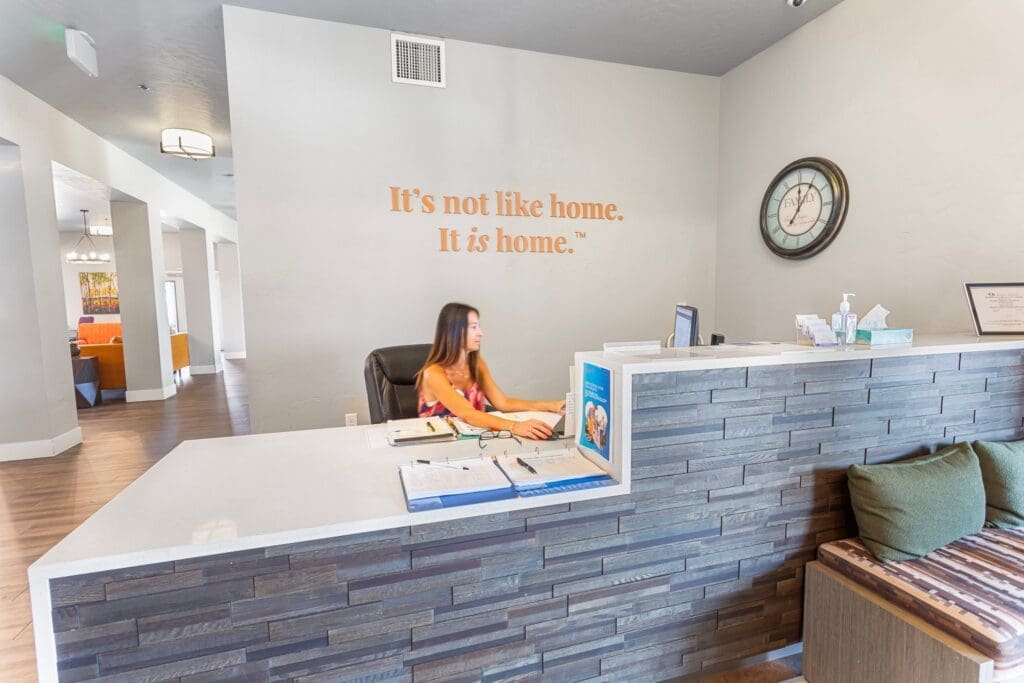 Warm, welcoming reception area featuring a team member assisting at a sleek front desk with vibrant decor in the background.
