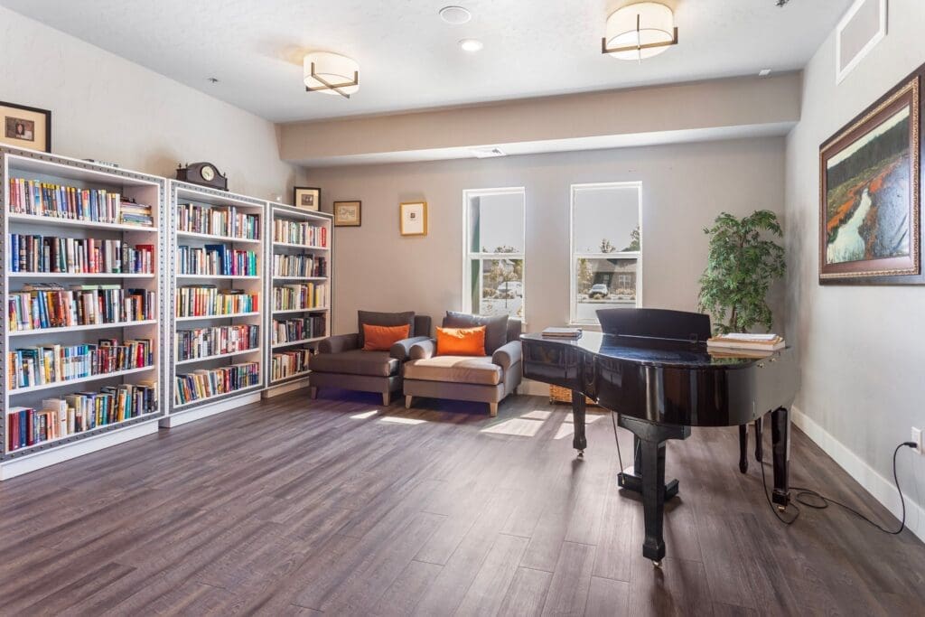 Warm, inviting lounge featuring bookshelves, cozy seating, and a grand piano enhancing vibrant community life.