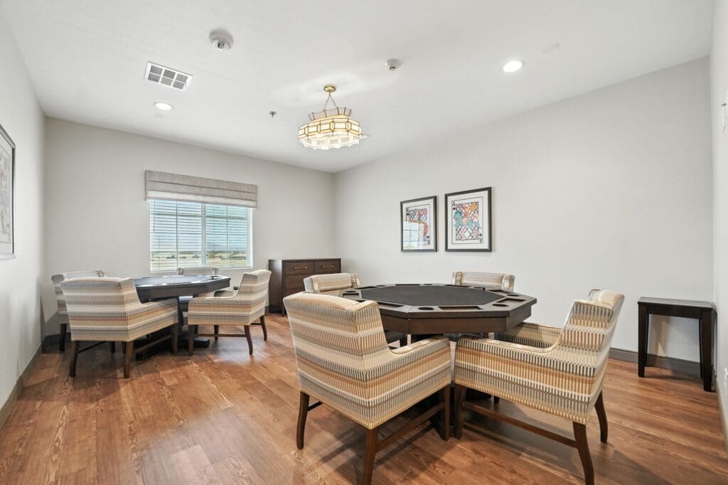Elegant activity room featuring sophisticated seating, a round table, and stylish artwork, promoting engaging social interactions.