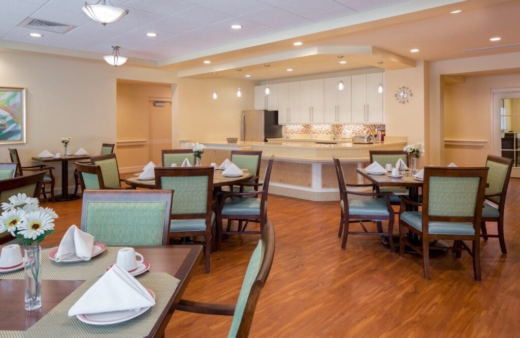 Inviting dining area featuring elegant tables, fresh flowers, and modern kitchen amenities, promoting a vibrant lifestyle.