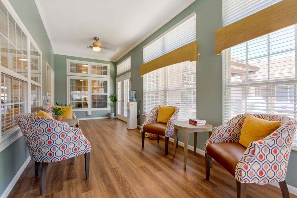 Bright, inviting lounge area featuring stylish chairs, a small table, and natural light through large windows.