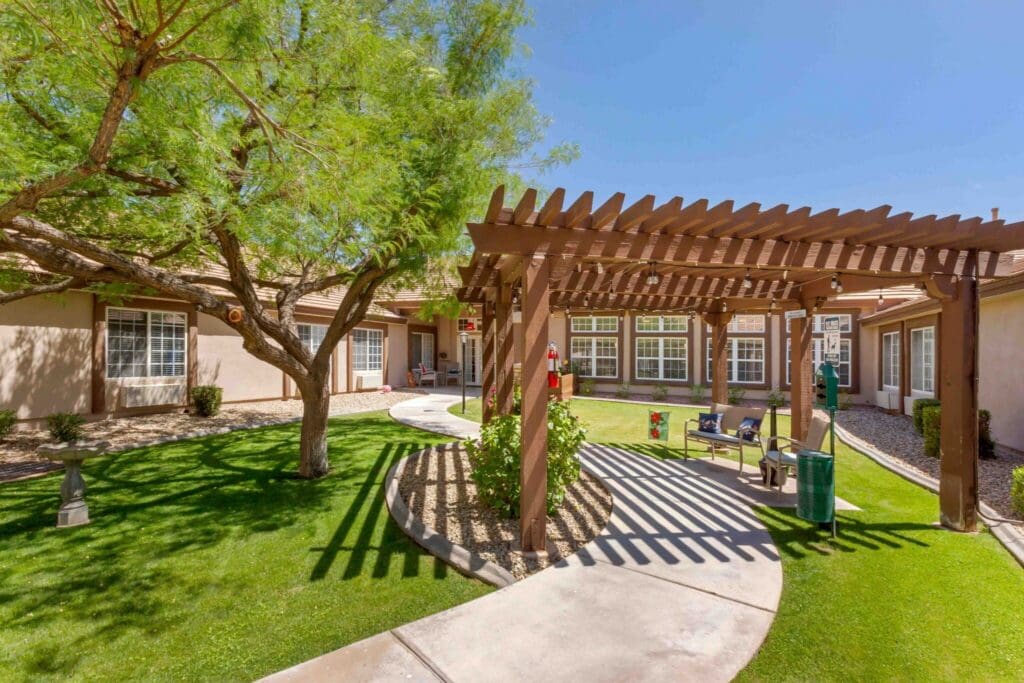 Lush courtyard featuring a pergola, pathways, and seating amidst vibrant greenery, enhancing a welcoming senior living environment.