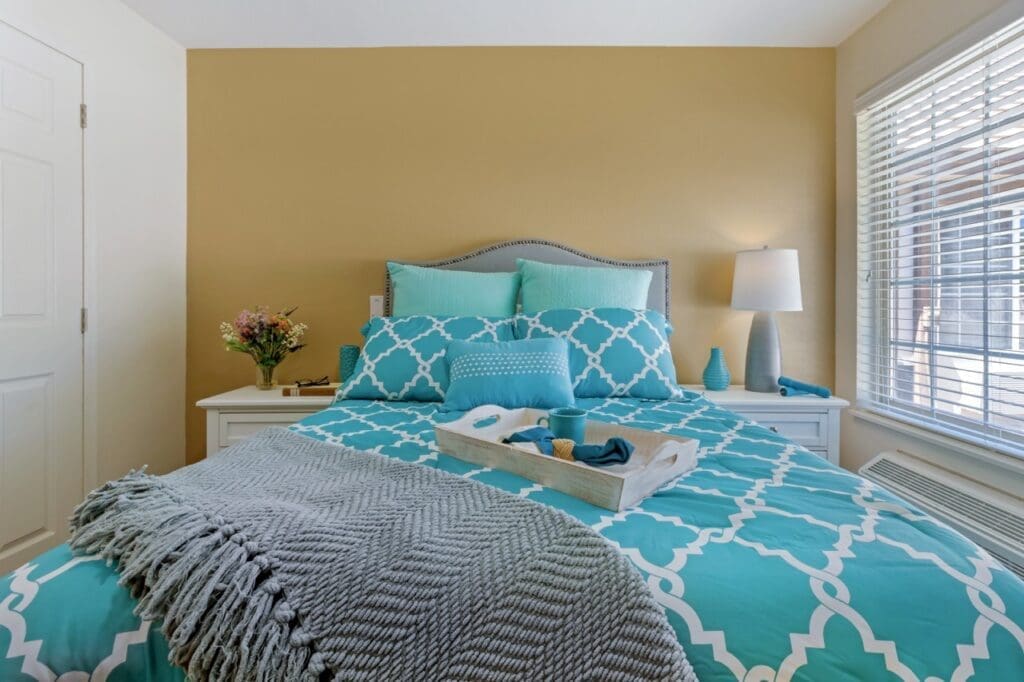 Inviting bedroom featuring turquoise bedding, cozy accessories, and natural light, creating a warm and uplifting atmosphere.