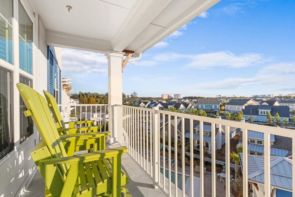 384-2048x1365 - Grace Management Bright, inviting balcony featuring green adirondack chairs, overlooking charming residential community and azure skies.