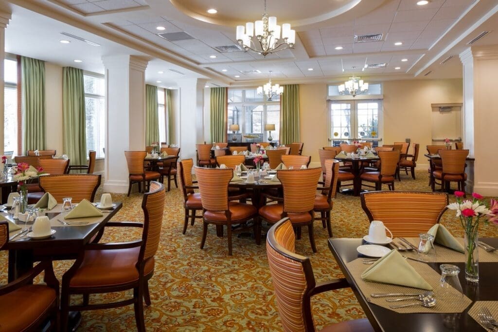 Elegant dining room featuring well-set tables, plush seating, and vibrant decor, ready for residents to enjoy meals together.