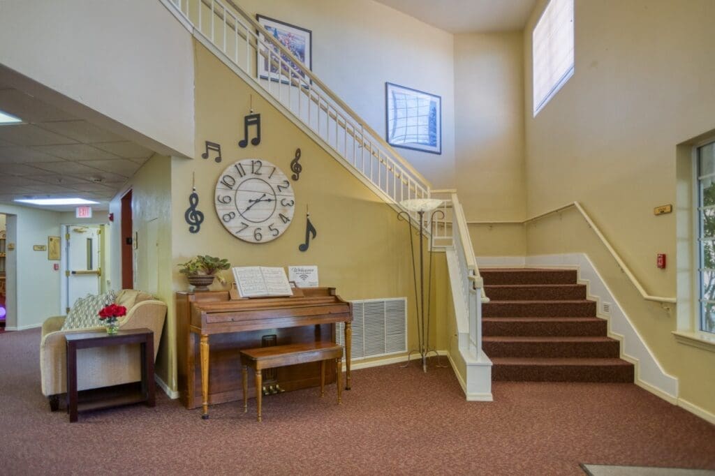 Welcoming lobby featuring a grand piano, stylish seating, a large clock, and music-themed decorations, promoting a vibrant atmosphere.