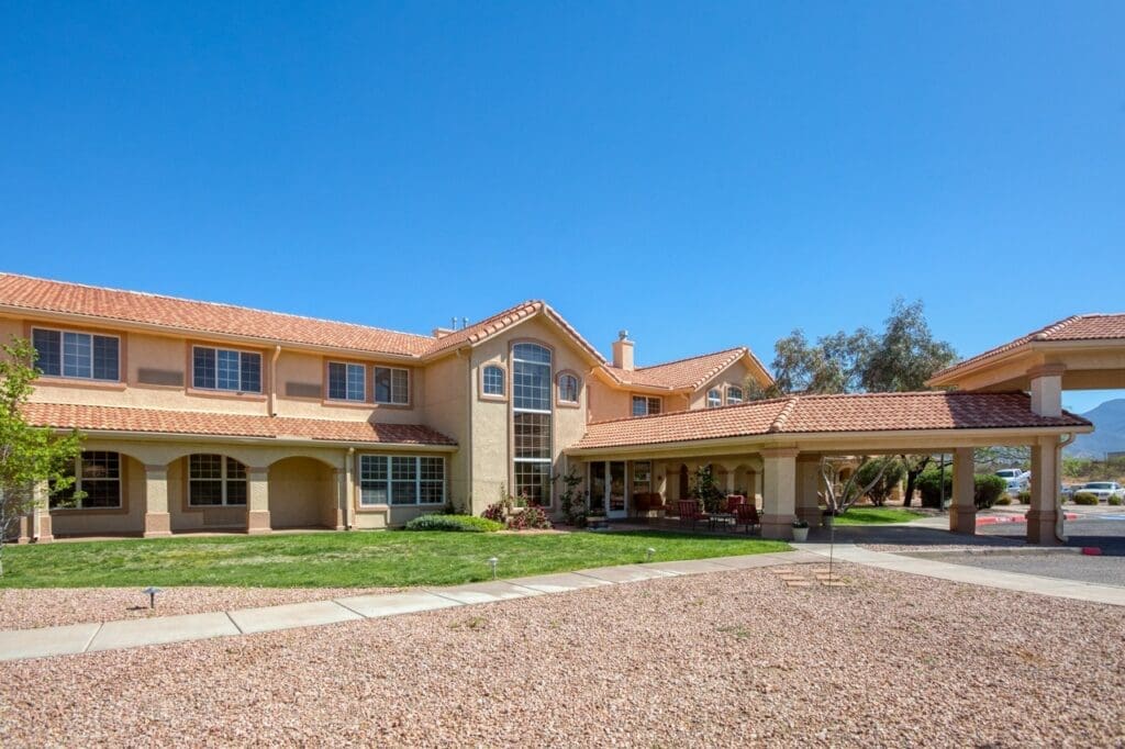 Vibrant senior living community with spacious architecture, manicured lawns, and inviting outdoor seating under clear blue skies.