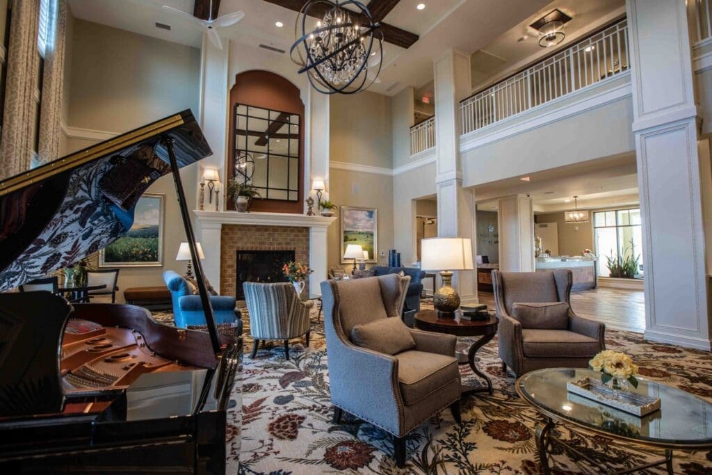 5H8A9753-2048x1365 - Grace Management Elegant lobby with a grand piano, plush seating, a cozy fireplace, and tasteful decor, inviting a vibrant social atmosphere.