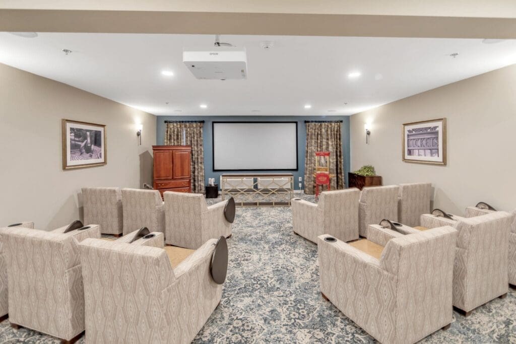 Comfortable seating arranged for movie viewing in an inviting lounge with warm decor and a large screen.