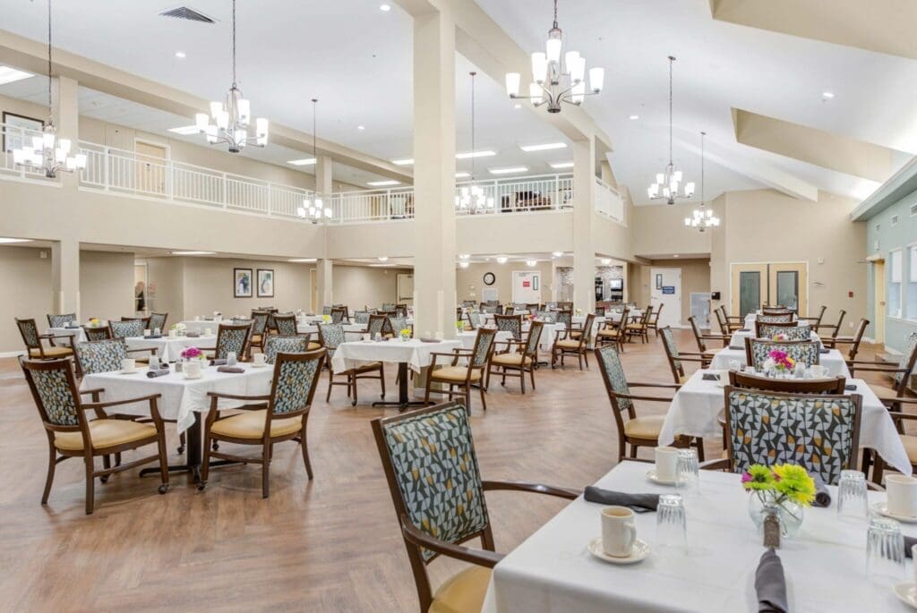 Spacious dining area with elegantly set tables, vibrant flowers, and bright lighting, promoting a welcoming dining experience.