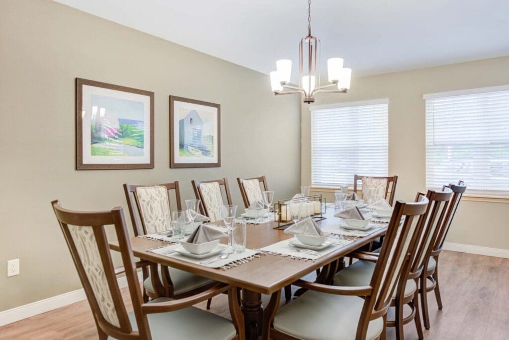 Elegant dining room featuring a beautifully set table for eight, decorated with tasteful tableware and soft lighting.