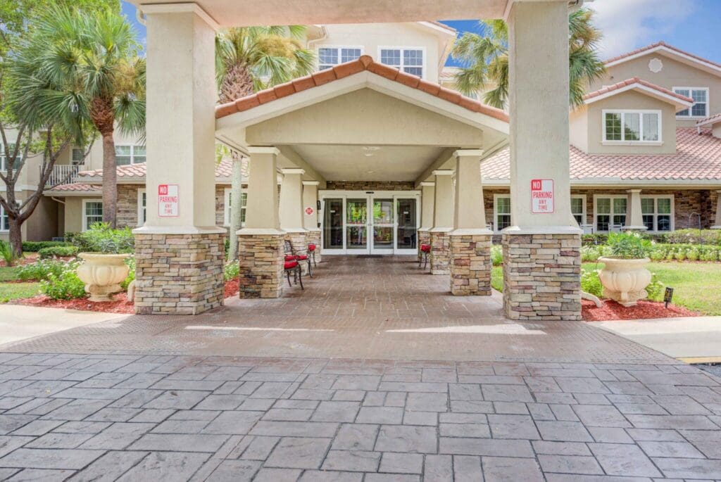 Elegant entrance of a senior living community with landscaped grounds, inviting seating, and a welcoming atmosphere.