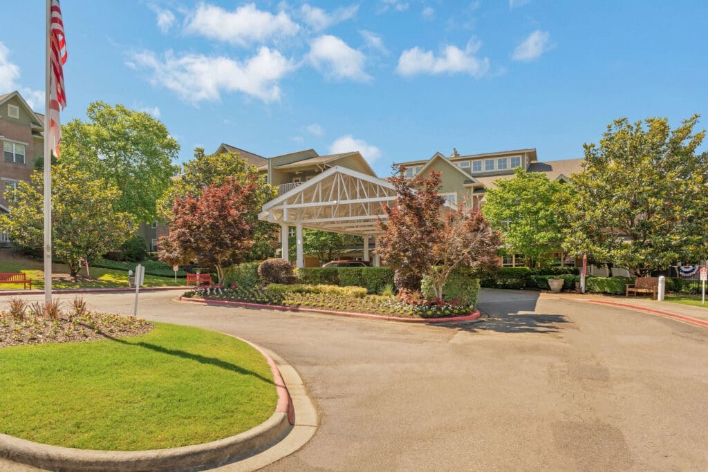 Welcoming entrance of a senior living community featuring upscale landscaping and a charming canopy for residents and visitors.